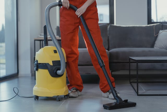 A professional cleaner in overalls vacuuming