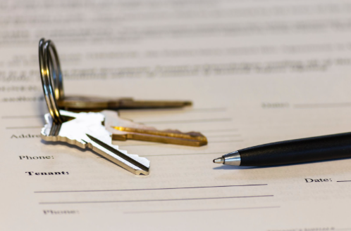 Keys and a pen on top of a rental agreement document. 