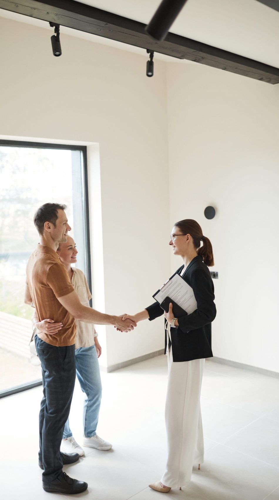 Vertical,Side,View,Portrait,Of,Young,Couple,Shaking,Hands,With people coming to an agreement in home