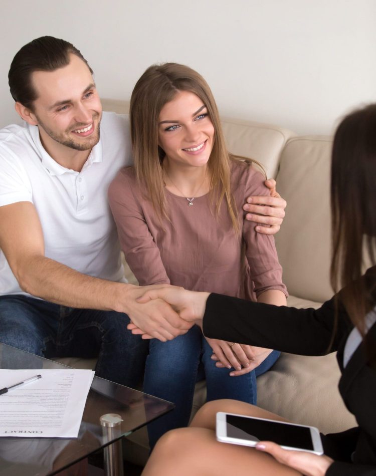 Happy,Cheerful,Couple,Shaking,Hands,With,Female,Travel,Manager,Or Young married couple talking with a real-estate agent visiting apartment for sale or for rent.